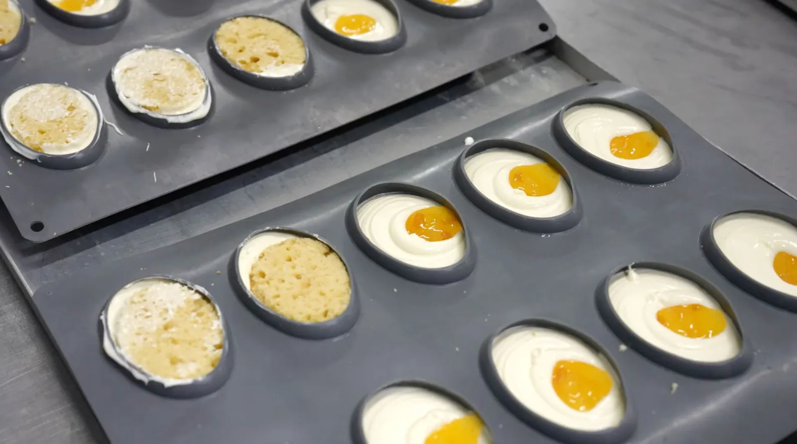 Produktion in der Frozen Cake Factory: Silikonformen mit Mousse und Fruchtkern auf dem Band